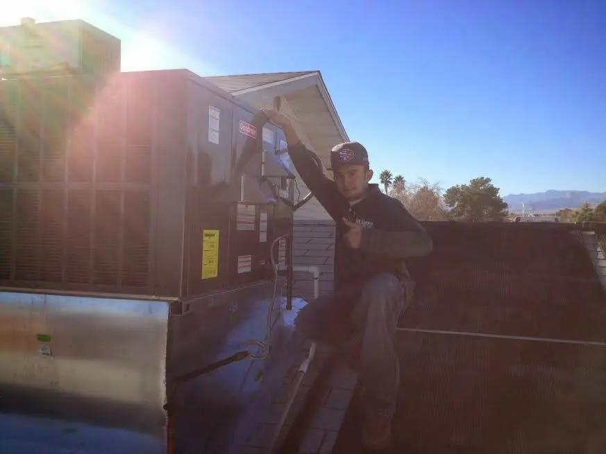 HVAC technician performing AC Tune-Up on a rooftop unit in Williams